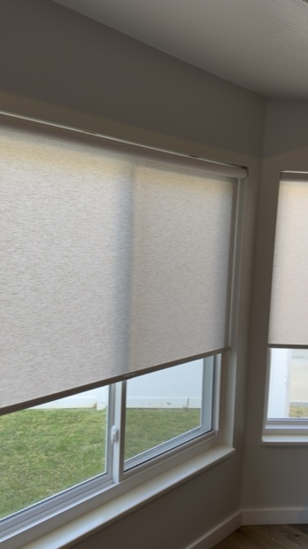 Close view of cordless roller shade fabric and cassette on a corner window