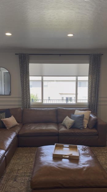 Roller shade partly lowered over a wide living room window